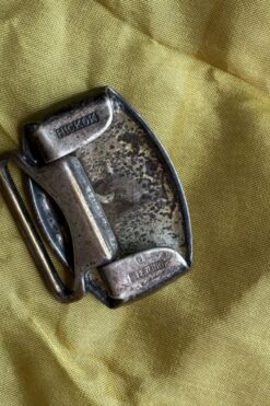 Rusty metal belt buckle on a yellow fabric background.
