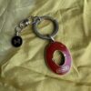 Coach keychain with a red oval tag and butterfly charm on a metal ring, laid on yellow fabric.