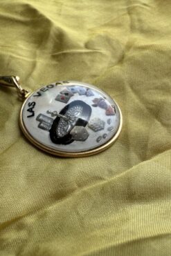 Las Vegas souvenir pendant on a gold chain rests on crumpled yellow fabric.